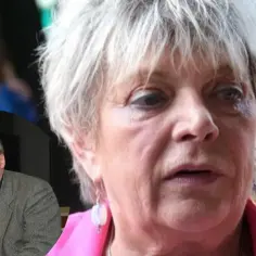 Dorota Stalińska z mężem. Mężczyzna w okularach przemawia przy mikrofonie, obok kobiety z siwymi włosami.