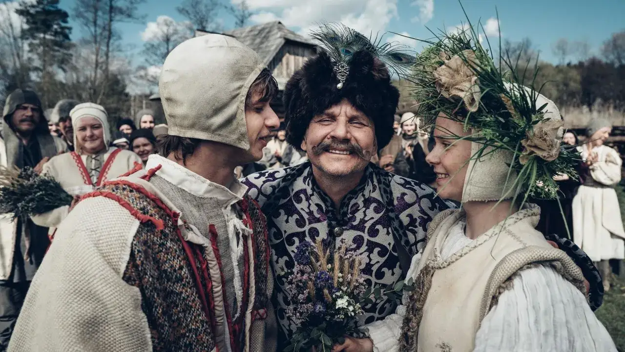 Uśmiechnięta obsada 1670: młody mężczyzna, starszy z pawim piórem na czapce i dziewczyna w wianku.